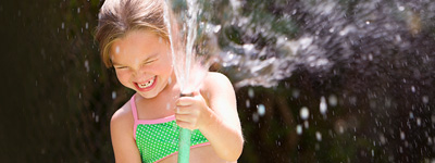girl playing with hose on warm summer day