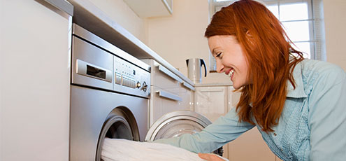 smiling woman pulling clothes out of energy efficient clothes washer