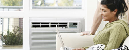 smiling woman on couch in front of room air conditioning unit