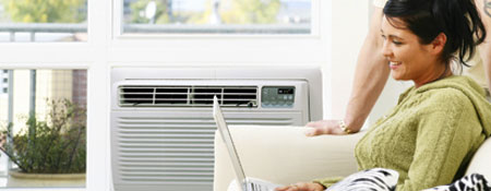 smiling woman on couch in front of room air conditioning unit